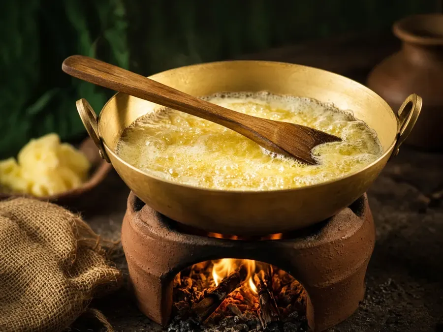 Butter simmering into ghee in a brass kadhai (illustrative)